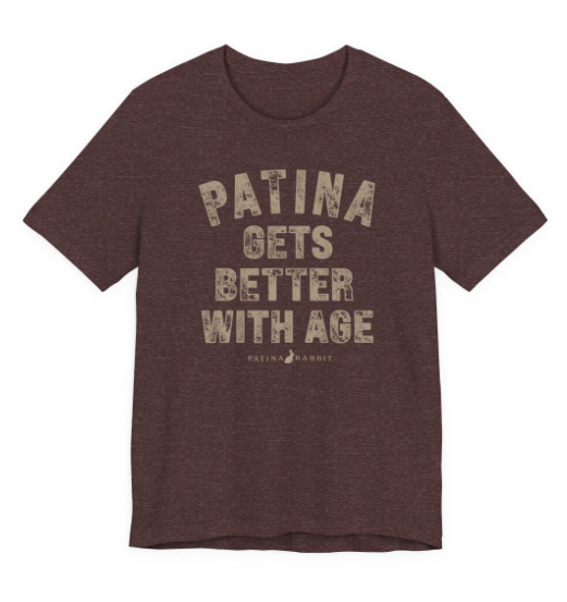 A heathered maroon crewneck t-shirt with a distressed beige graphic text that reads 'PATINA GETS BETTER WITH AGE' and a small 'PATINA RABBIT' logo underneath,