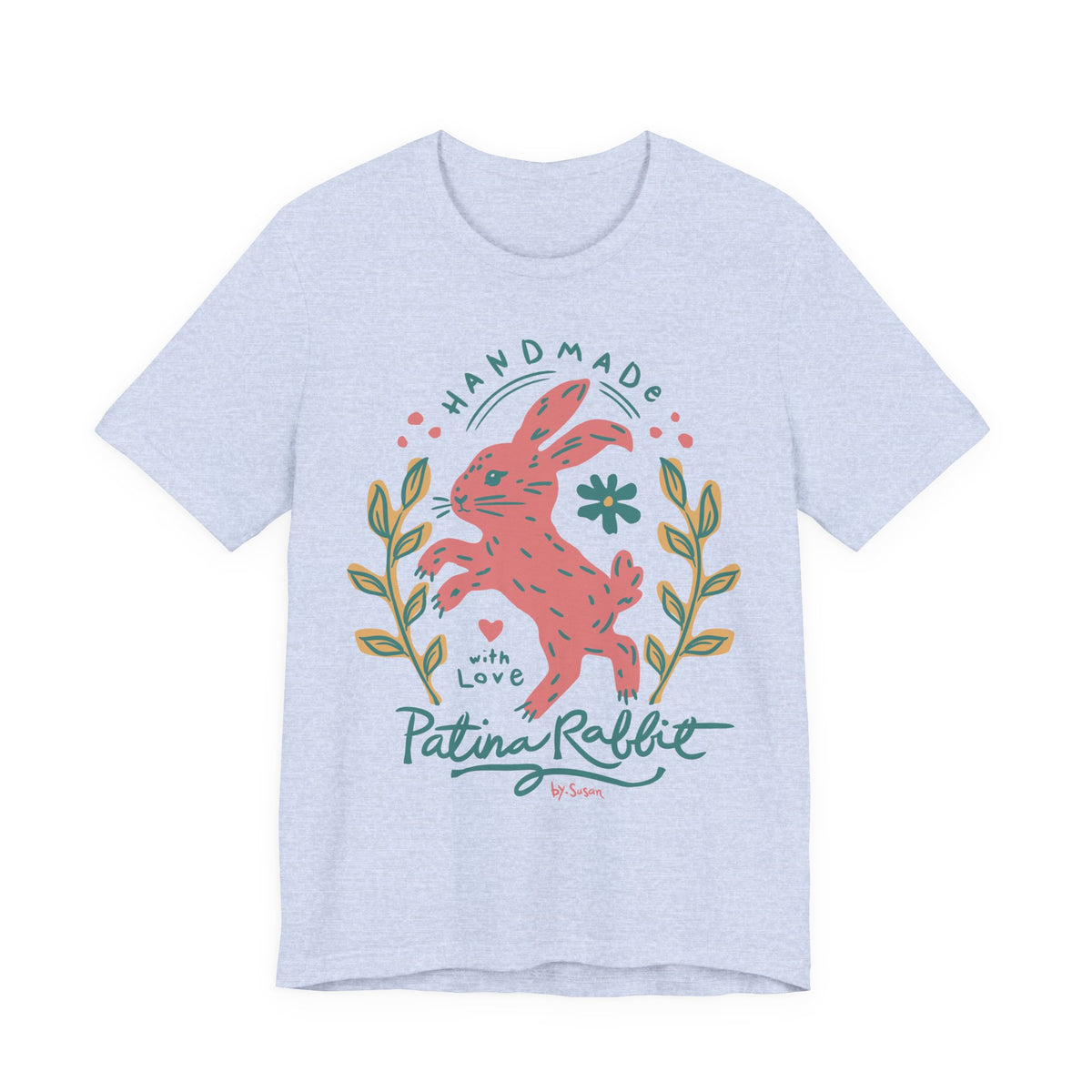 A light heather blue short-sleeve t-shirt with a colorful graphic of a pink rabbit, green leaves, and the text 'HANDMADE with Love Patina Rabbit' on the front, shown against a plain white background.