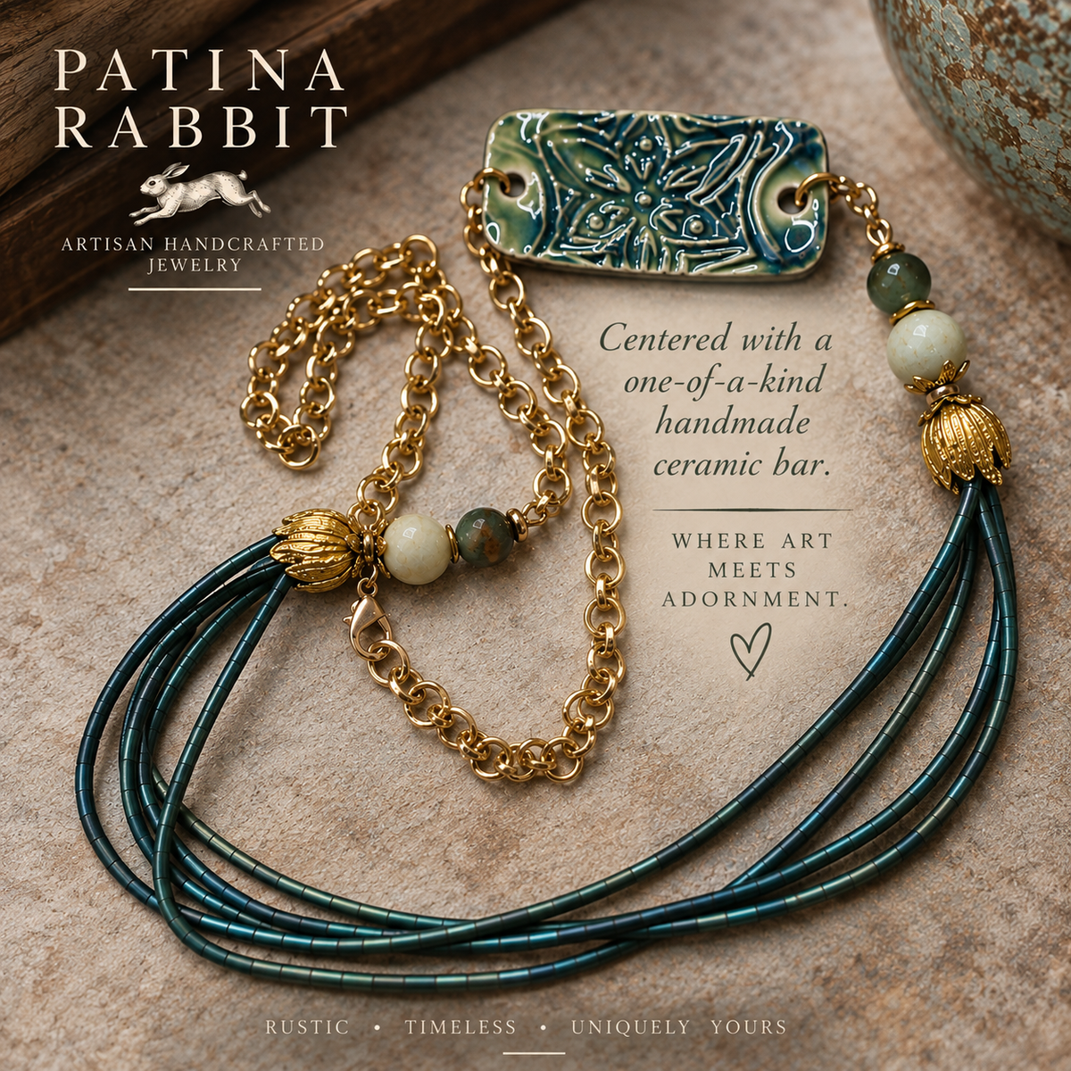 A Patina Rabbit handmade jewelry piece featuring a gold chain, multiple strands of dark teal-green cord, decorative beads, and a carved ceramic bar pendant, styled on a textured stone surface with promotional text.