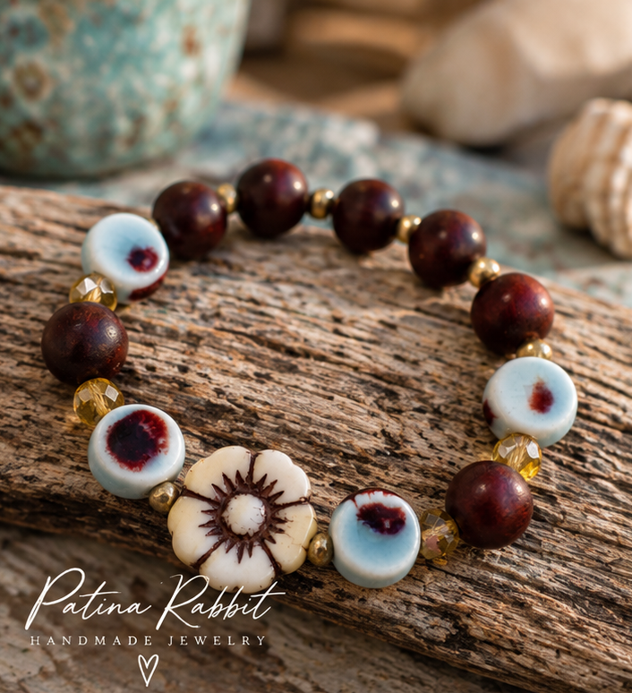 Patina Rabbit handmade stretch bracelet with rosewood beads, aqua ceramic beads, cream flower bead and gold accents.